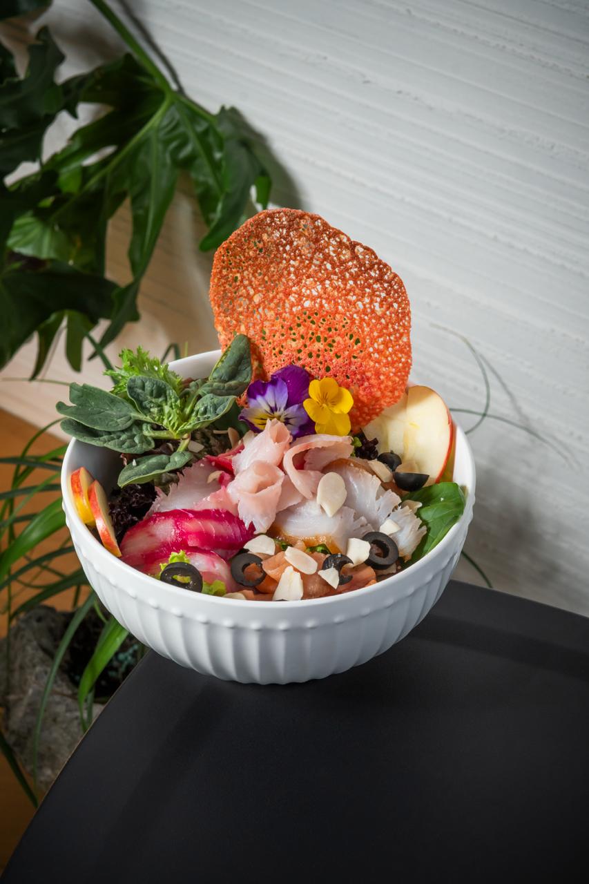 Bowl de sashimi mixto con tuile crujiente y flores comestibles.